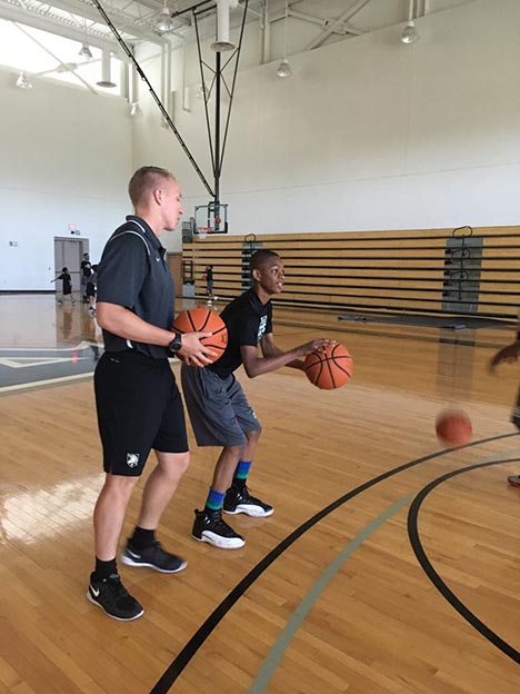 Coach teaching basket ball to new player 