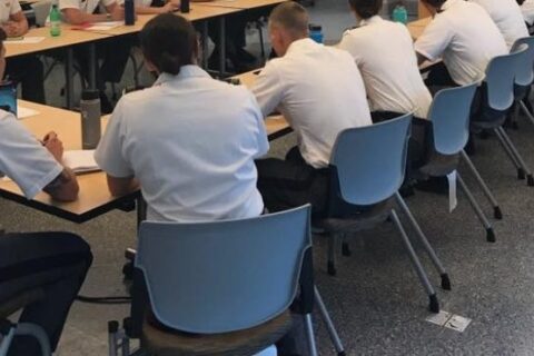 Boys sit on the chairs and attain a meeting in the hall