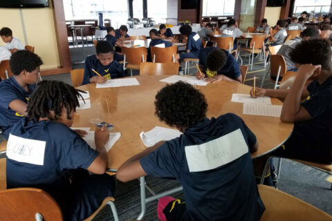 Group of students sitting around a a table taking notes