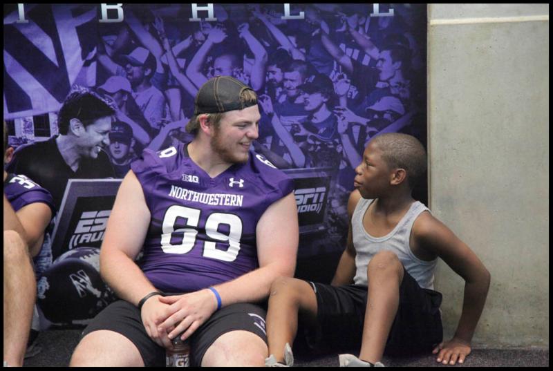 Football player interacting with a student