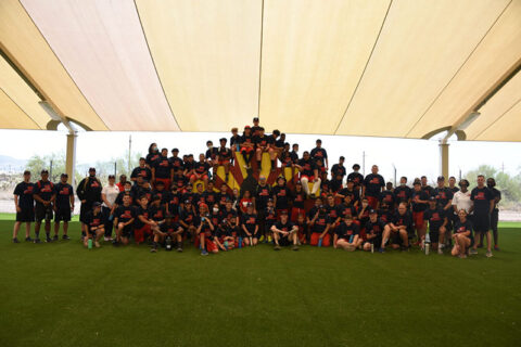 Group of adults and children in black tee on the ground posing for the photograph