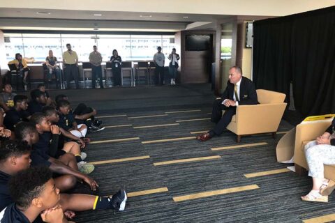 Man addressing a group of young boys in the hall