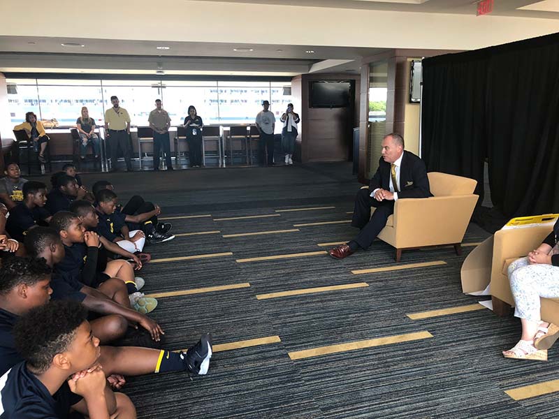 Man addressing a group of young boys in the hall