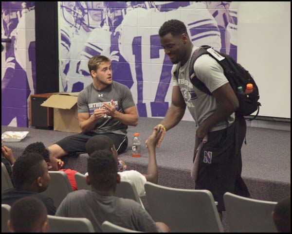 Adults shaking hands with students