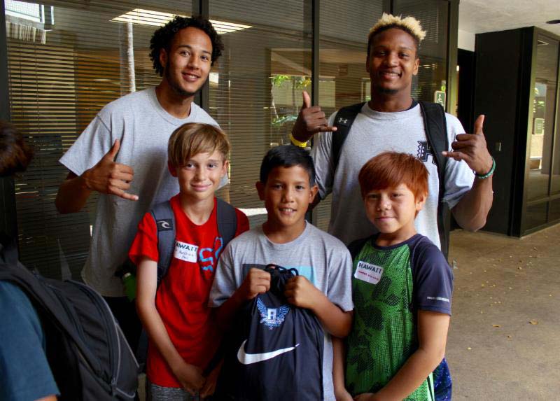 3 boys along with their coach posing for the photograph