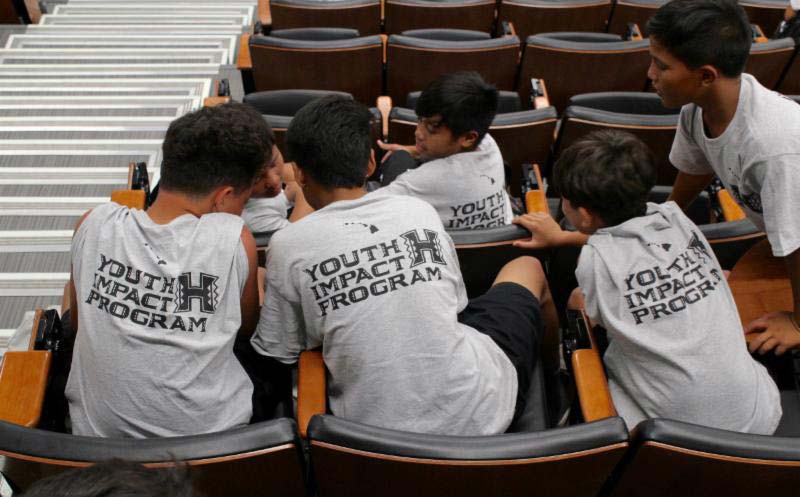 Students wearing 'Youth Impact Program' tshirts sitting in the classroom