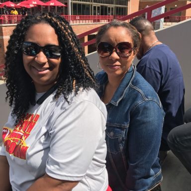 2 women sitting in the stadium and posing for photo