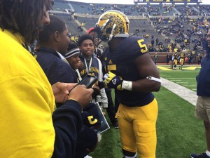 Football player talking to group of students