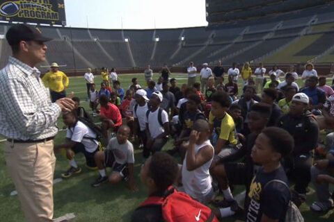 students sitting on ground with teacher giving speech