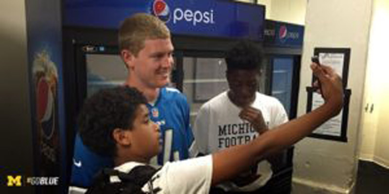 Student talking selfie with football player
