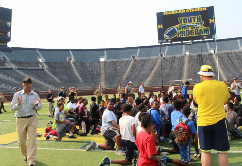 Students and adults sitting on a football ground