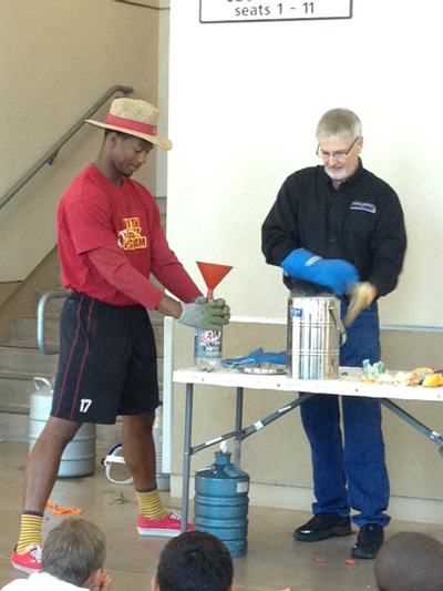 Coach and football player demonstrating something to students