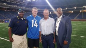 4 men's smiling for the photograph in the stadium