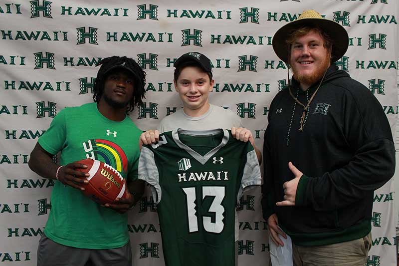 Boy holding a black jersey standing with his instructors