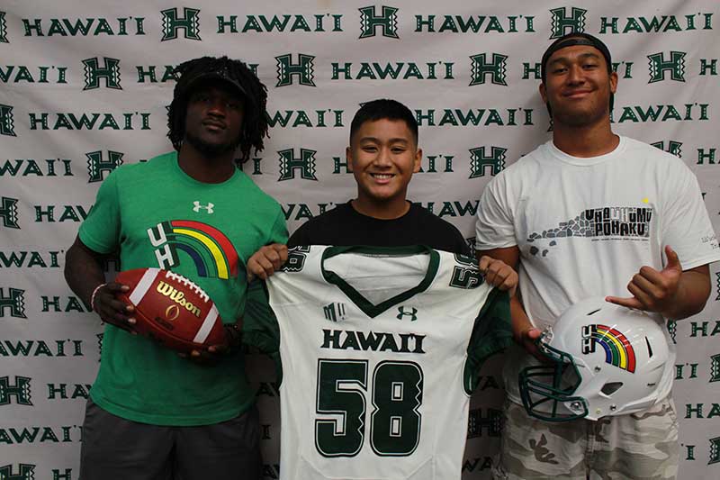 Boy holding a white jersey standing with his instructors