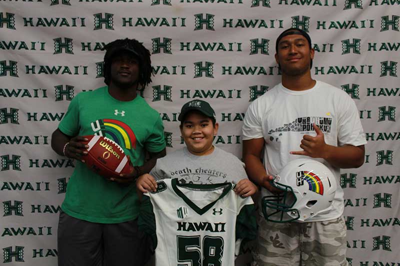 Boy holding a white jersey standing with his instructors