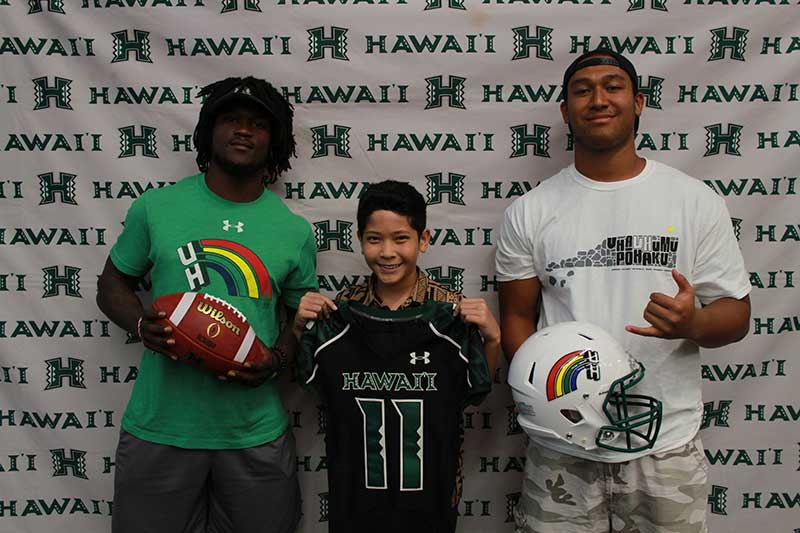 Boy holding a black jersey standing with his instructors