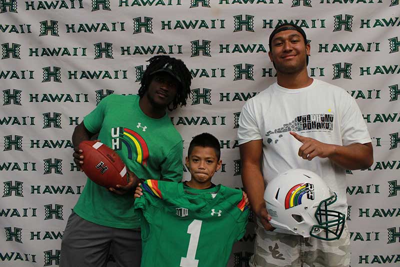 Boy holding a green jersey standing with his instructors