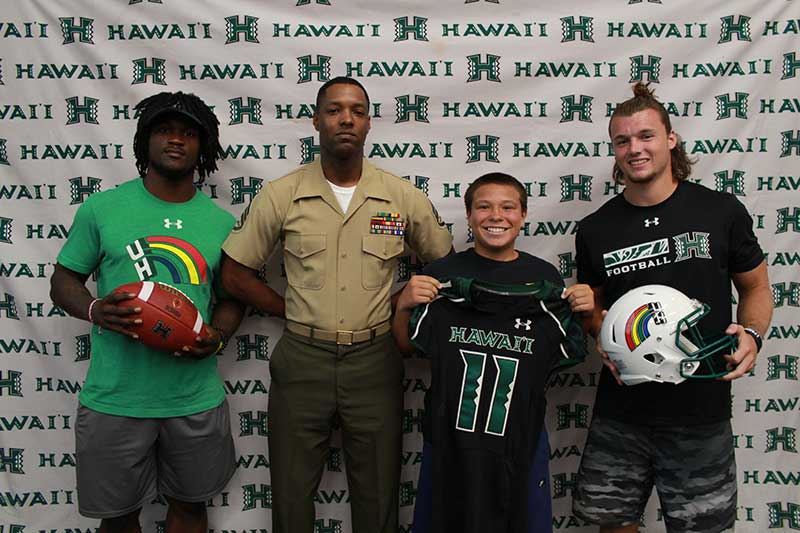 Boy holding a black jersey standing with his instructors