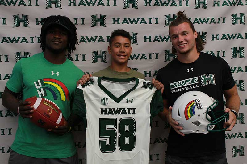 Boy holding a white jersey standing with his instructors