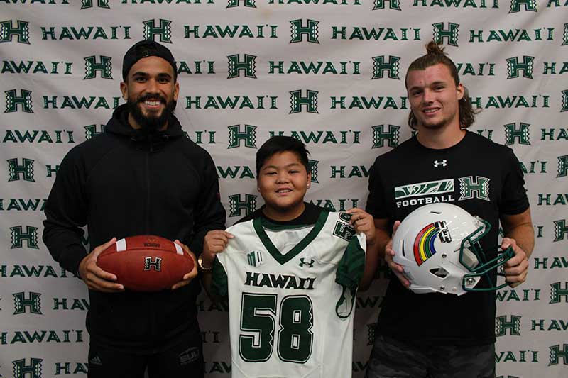 Boy holding a white jersey standing with his instructors