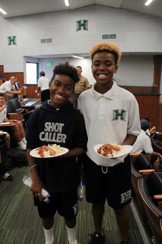 2 boys standing and holding food plates