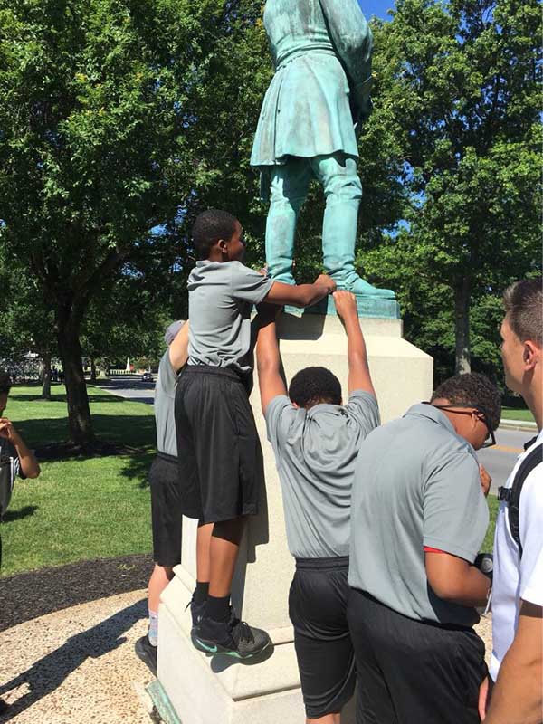 Student standing on the statue's pillar