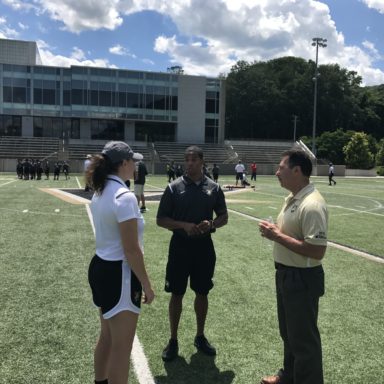 Students in the ground and sport coaches talk with 