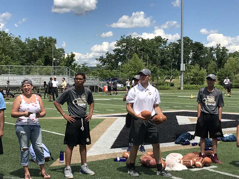 Coach holding basket ball and students standing beside a coach in the ground